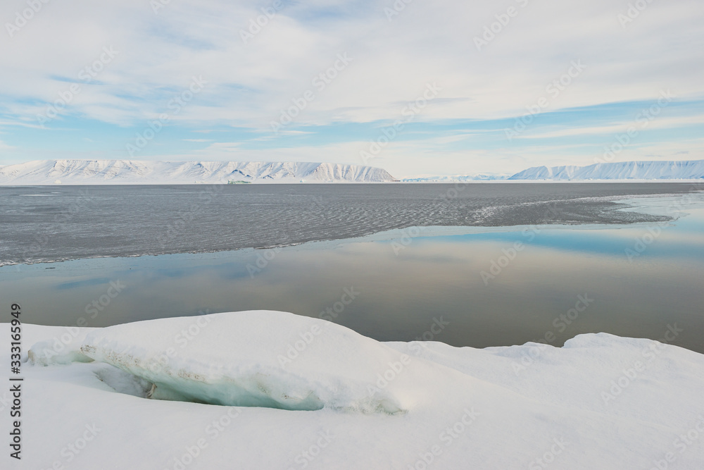 Open water at fjord in front of mountain range, Greenland.