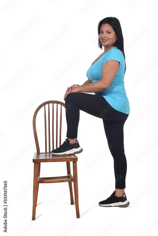 woman playing with a chair in white background, with the foot in the chair and looking at camera woman playing with a chair in white background, with the foot in the chair and looking at camera