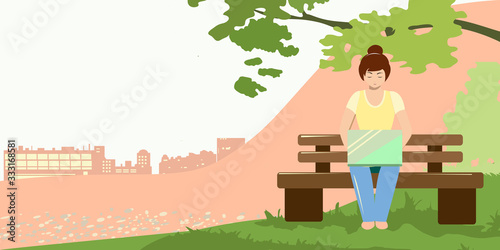 Girl works behind a computer in the park on a warm day alone