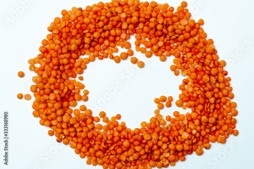 circle laid out of red lentils on a white background. place for text. group. legumes. grocery