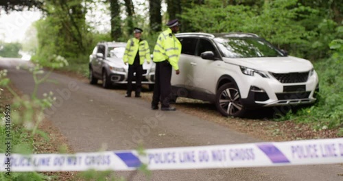 4K Police investigating a vehicle at crime scene, cordoned off with police tape. Slow motion.