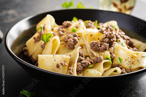 Pasta Calamarata with minced meat in black bowl. Italian cuisine. photo