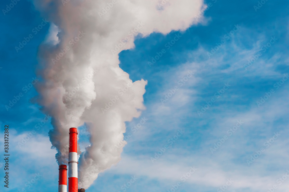 Environmental pollution, environmental problem, smoke from the chimney of an industrial plant or thermal power plant on a background of blue sky with clouds