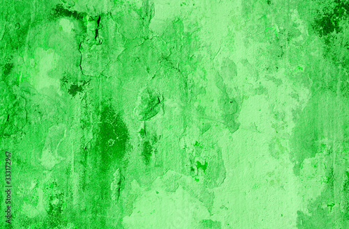 Green background. Wall with peeling plaster, tinted in green. Modern urban building concept. Bright neon backdrop. Selective focus