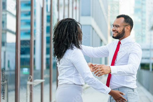 Happy old friends happy meeting in city. Business man and woman standing outside, smiling and opening hands for hug. Joyful meeting concept