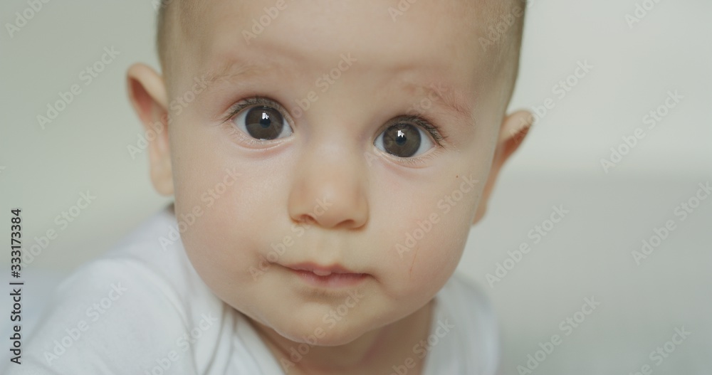 Authentic close up shot of a a cute newborn baby with brown eyes is looking in the camera. Concept of children,baby, parenthood, childhood, life, authenticity
