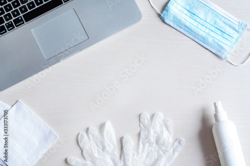 Fotografie flat lay remote work kit on wooden office desk with hand sanitizer, face mask, gloves,  solution against the spread of coronavirus for quarantined employees