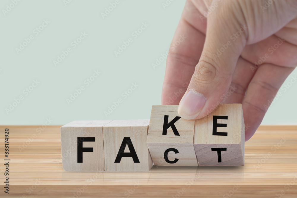 Naklejka premium Hand flip wood cube change the word Fact or Fake. April fools day concept.