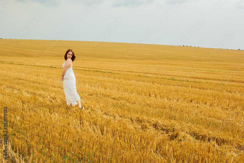 Good outdoor recreation. Young beautiful redhead woman in the middle of a wheat field, having fun. Summer landscape, good weather. Windy day with the sun and clouds. White cotton dress, eco style. Good outdoor recreation. Young beautiful redhead woman in the middle of a wheat field, having fun. Summer landscape, good weather. Windy day with the sun and clouds. White cotton dress, eco style.