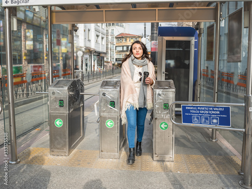 Fotografie Beautiful young girl uses metrocard to pay the commuter fare and enter turnstile in transit system in Istanbul,Turkey