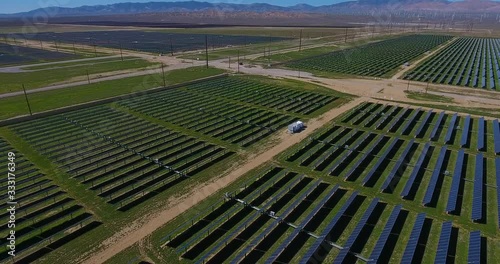 aerial over solar panel field toward mountains and wind turbines