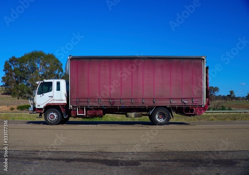 Truck on a freeway in Australian Country Town midway between Sydney and Melbourne with nice blue sky and lush green trees as a backdrop