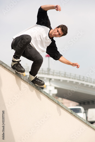 Closer picture of handsome concentrated professional young man skating and training outside. Doing stunts alone professionally. Vertical picture.