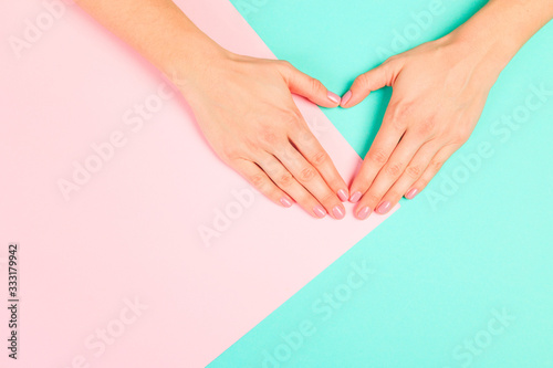 Fototapeta Naklejka Na Ścianę i Meble -  female  manicure. Beautiful young woman's hands in heart shape on pastel   background- Image
