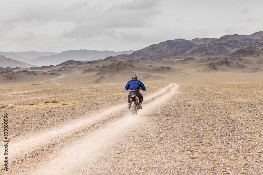 Man riding a motorbike in the steppes of Mongolia, on the hills of Mongolia