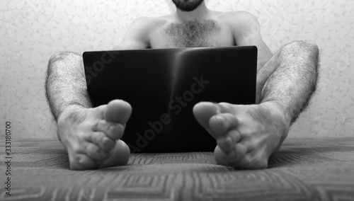 Picture Of Young Naked Man With Hairy Legs Sit On Sofa And Hold Laptop  Between Feet Cover Himself With Device Screen Low View Black And White  Picture Cut View 1 Wall Mural |-