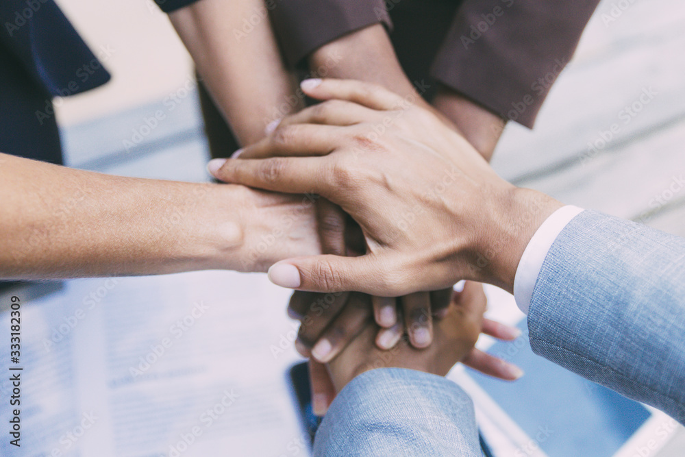 Business team putting their hands together, expressing unity, support, friendship. Closeup of people stacking hands. Teamwork and success concept