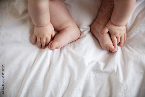 Close up of a babies hands and feet on a white bed sheet