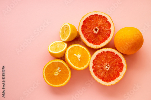 Various halves of citrus fruits on a pink background