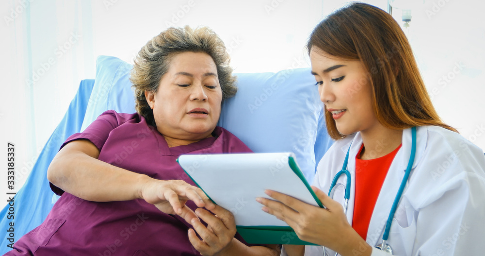 Doctor meeting and explaining medication to old woman patient lying in bed at Hospitals Doctor meeting and explaining medication to old woman patient lying in bed at Hospitals