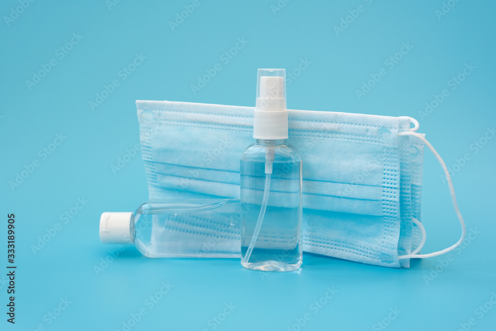 Set of antiseptic items. Wearing mask, bottles of antiseptic hand gel and spray on blue background. Flu, illness, pandemic concept Set of antiseptic items. Wearing mask, bottles of antiseptic hand gel and spray on blue background. Flu, illness, pandemic concept