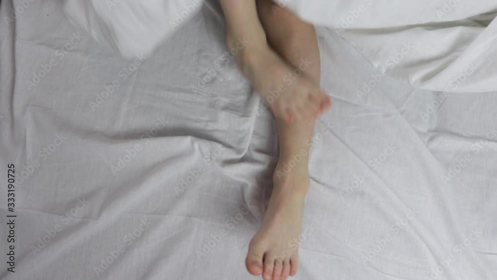 naked beautiful legs under the blanket. one leg scratched the other while sleeping. naked beautiful legs under the blanket. one leg scratched the other while sleeping.