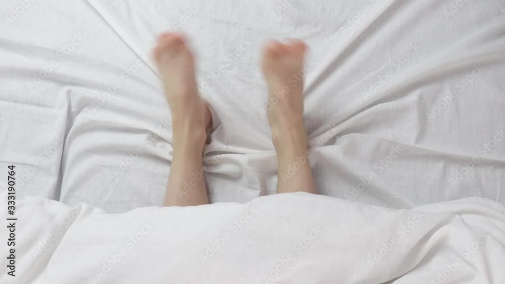 naked beautiful legs under a white blanket. both legs were under the covers. naked beautiful legs under a white blanket. both legs were under the covers.