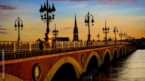 Selective focus of Pont de Pierre bridge and motion blur of tram in Bordeaux at sunset as the night sky scene