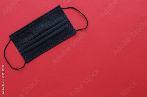 Black protective mask on a red background, space for text