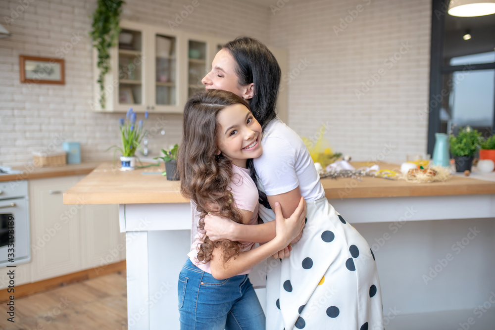Brunette woman and her cute daughter hugging each other Brunette woman and her cute daughter hugging each other