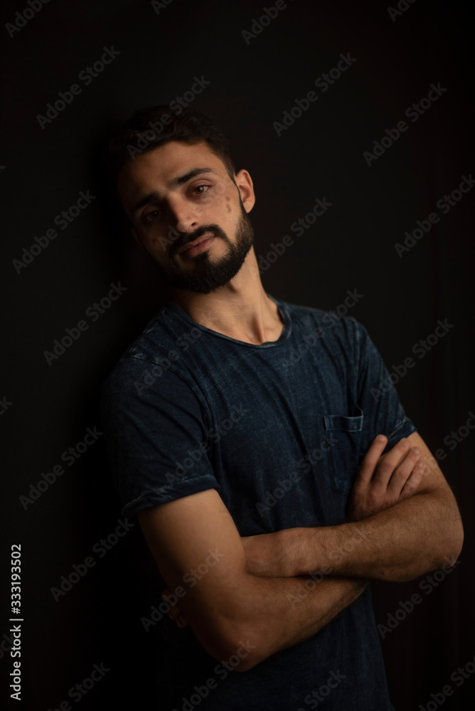 Portrait of young brunette Indian Kashmiri man in casual tee shirt in black copy space studio background. lifestyle and fashion.