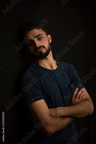 Portrait of young brunette Indian Kashmiri man in casual tee shirt in black copy space studio background. lifestyle and fashion. © abir