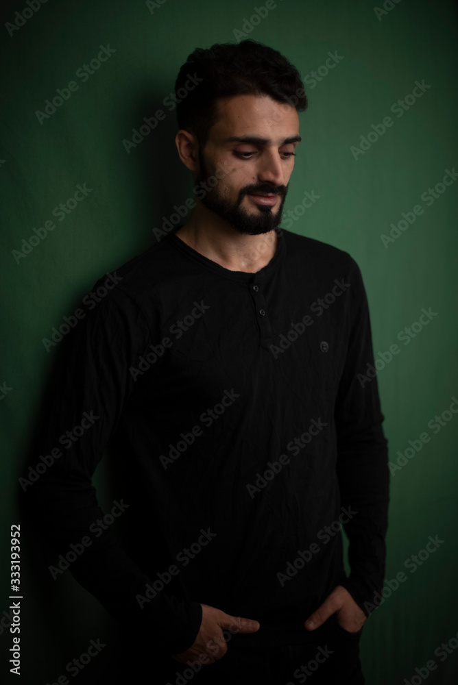 Portrait of young brunette Indian Kashmiri man in casual tee shirt in green copy space studio background. lifestyle and fashion.