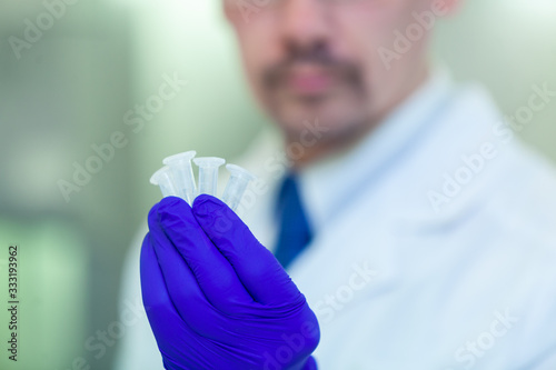 A scientist holding a sample with a hand in a blue glove. COVID-19. COVID Coronavirus