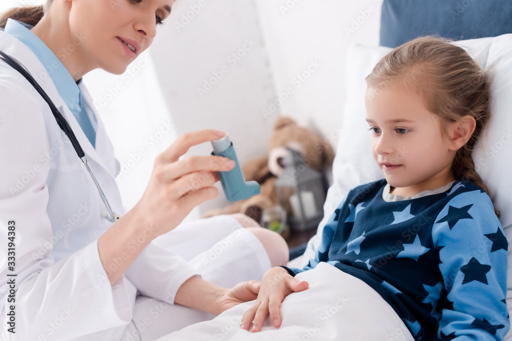 doctor in white coat holding inhaler near asthmatic child