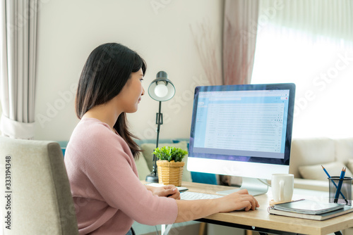 Young asian businesswoman using computer checking e-mail work from home for protect virus and take care of their health from COVID-19. Working at home and social distancing concept.