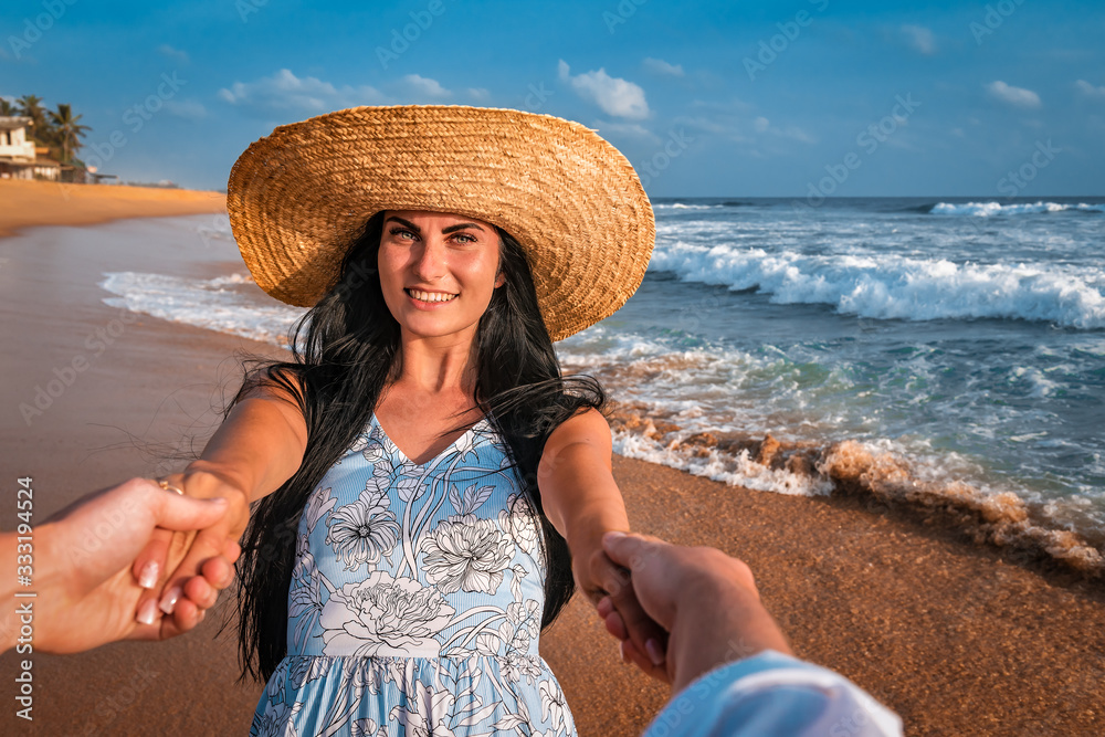 girl holds her boyfried hands on the beach