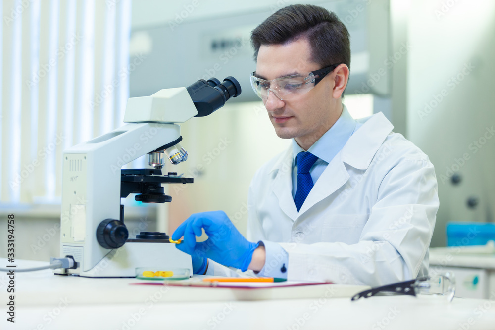 Scientist studies properties and benefits of omega 3 fatty acids using microscope and laboratory equipment in a medical laboratory. COVID-19. COVID Coronavirus Scientist studies properties and benefits of omega 3 fatty acids using microscope and laboratory equipment in a medical laboratory. COVID-19. COVID Coronavirus
