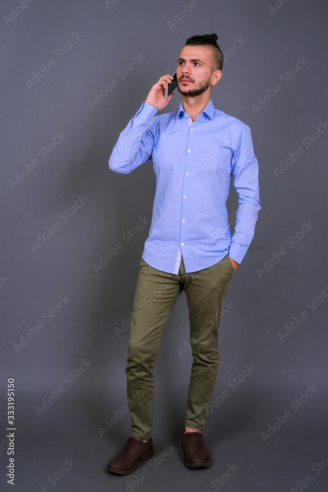 Handsome Turkish businessman using mobile phone against gray background