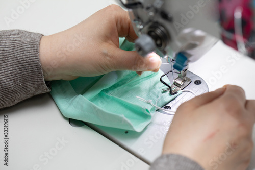 Experienced seamstress sews fabric protective masks as standard during the COVID-19 epidemic.