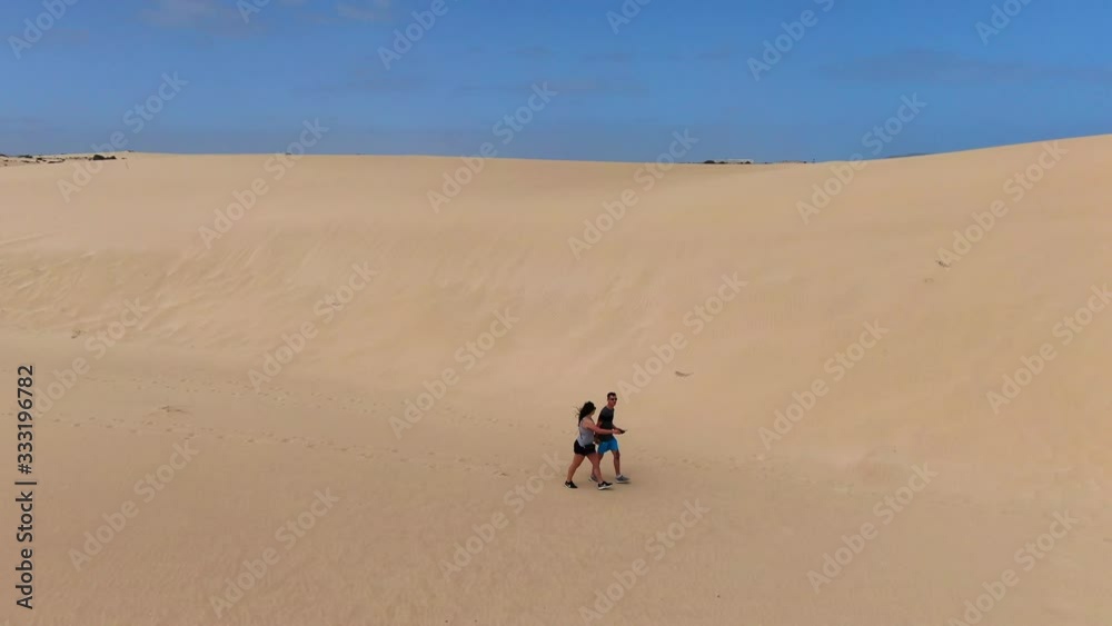 Aerial view on Young Couple, walking on sand dunes in Corralejo, Fuerteventura, Canary Islands, Spain Aerial view on Young Couple, walking on sand dunes in Corralejo, Fuerteventura, Canary Islands, Spain