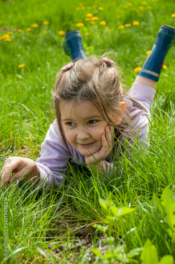 Sweet little girl take a rest on the grass in the garden