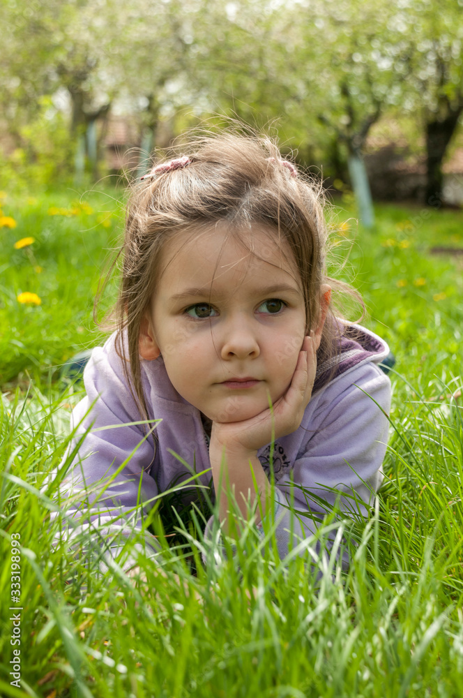 Sweet little girl take a rest on the grass in the garden