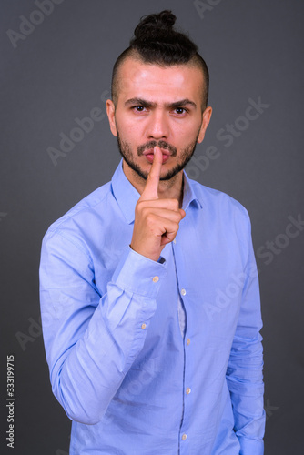 Portrait of serious bearded Turkish businessman with finger on lips