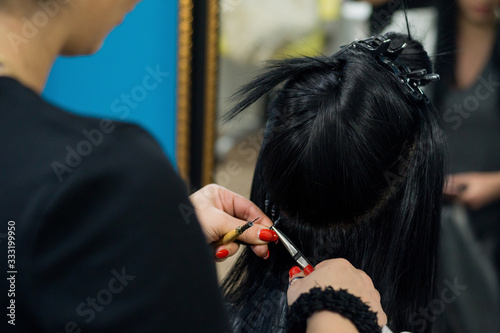 Professional woman applying hair extensions with different types of grips. Nano rings extensions made from real humas hair. photo