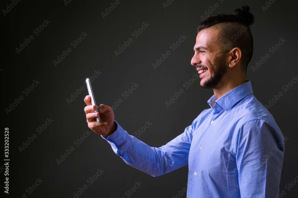 Profile view of happy bearded Turkish businessman using phone