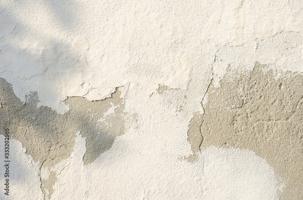 Obraz premium gray wall of old house closeup. White peeling plaster. Cracks on the surface of building or fence. City building concept. Copy space. Place for text. Selective focus image.