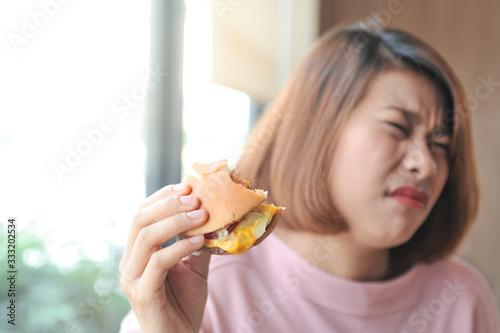 Unpalatable food makes not enjoy eating  A girl was fulled after eating burger Burger is hight calories food Selective focus