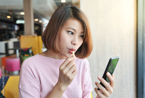 Wallpaper Mural A woman eating french fries and looking to her smart phone,Eating and shoping online in smart phone,Investment on mobile phone,Selective focus Torontodigital.ca