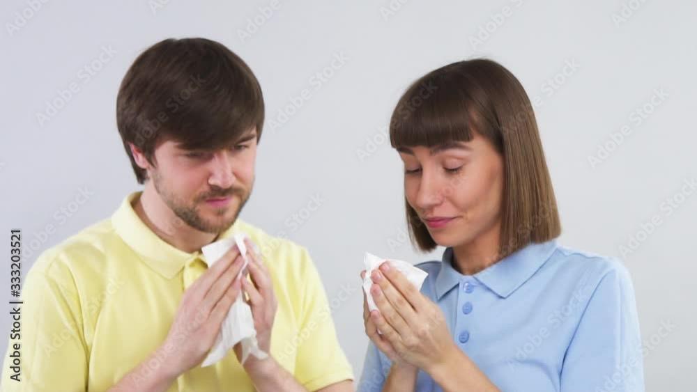 happy couple with tissue in arms smiling after blowing their noses and looking at each other with thumbs up happy couple with tissue in arms smiling after blowing their noses and looking at each other with thumbs up